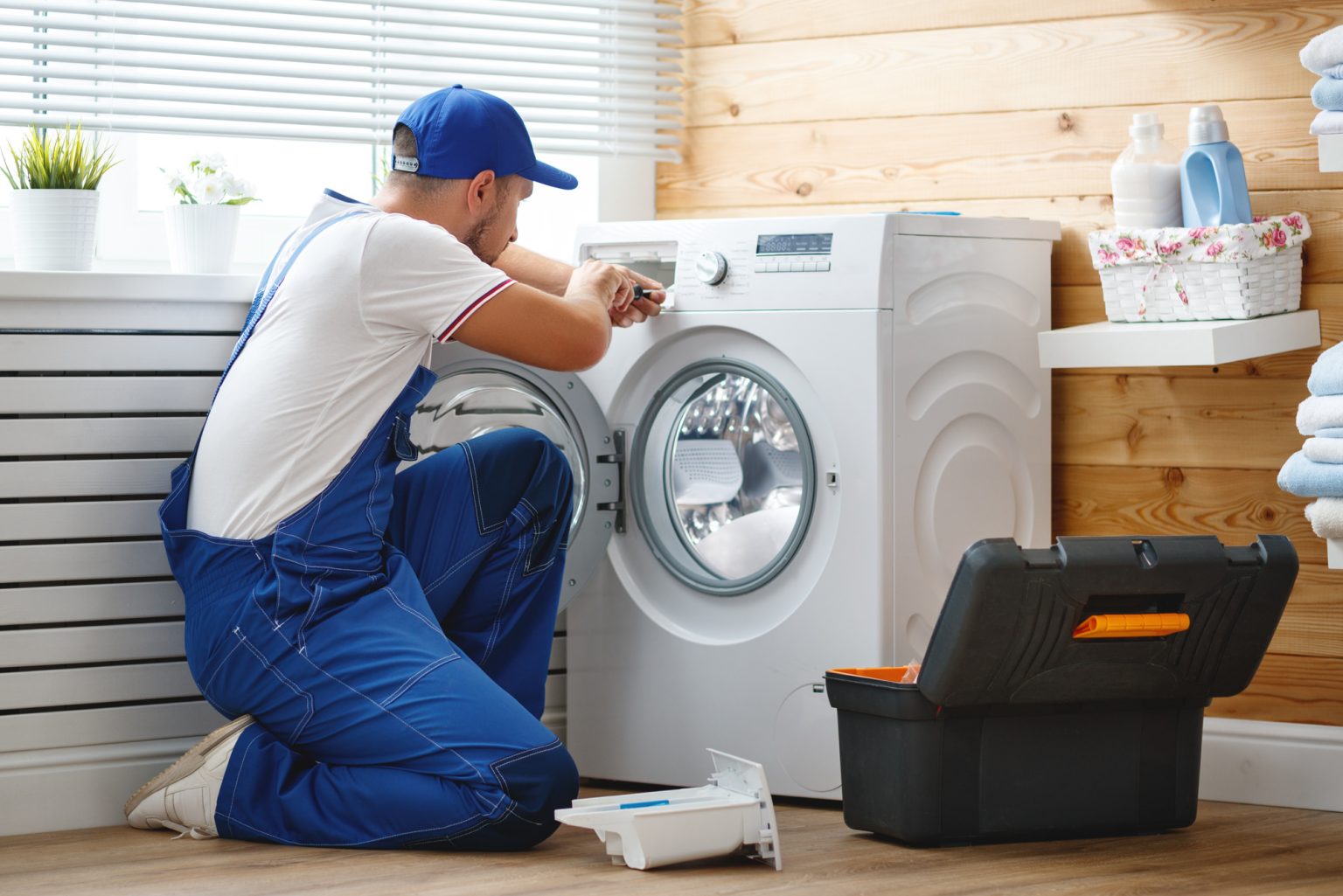 working man plumber repairs a washing machine in   laundry